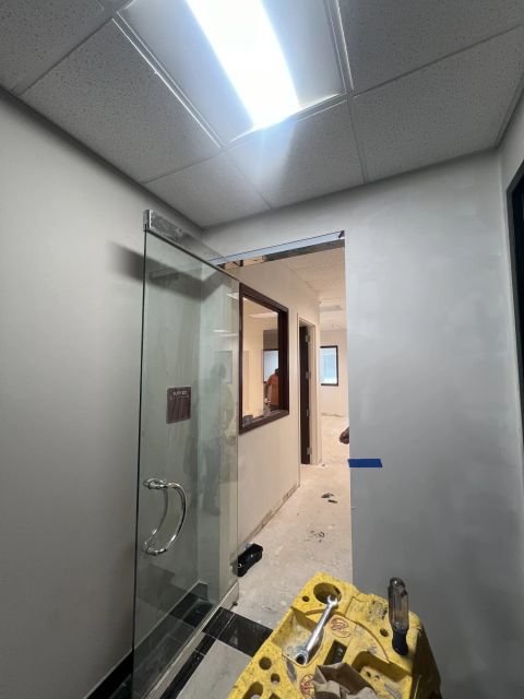 Glass door installation beside an unfinished office corridor, in progress