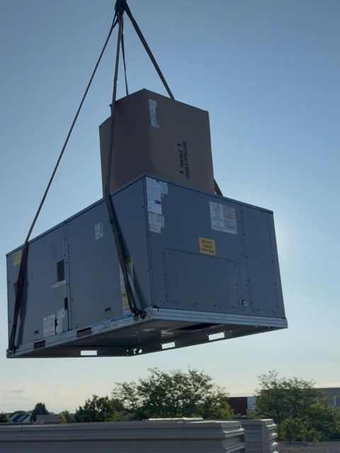 Close view of a rooftop HVAC unit suspended from a crane