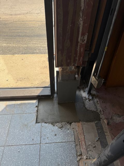Repaired steel column base at glazed entry