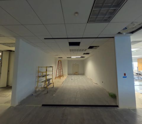 Office room with a scaffold, ladder, and unfinished floor, in progress
