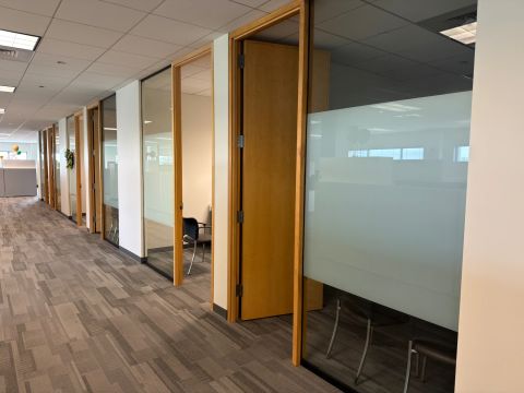 Wood-framed glass offices and open doors along a commercial corridor